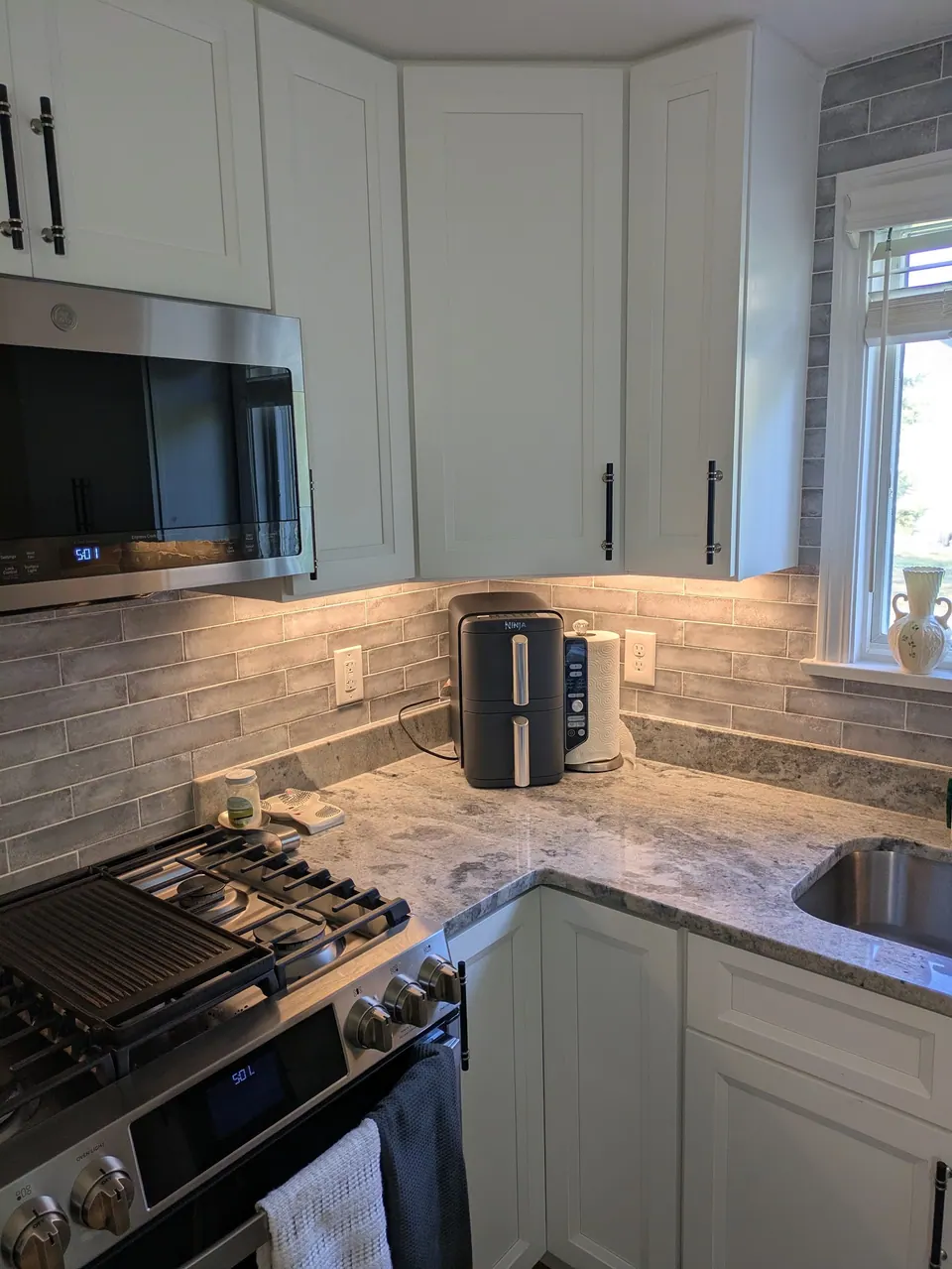 White wall cabinets with an angled corner cabinet above the range and sink corner.