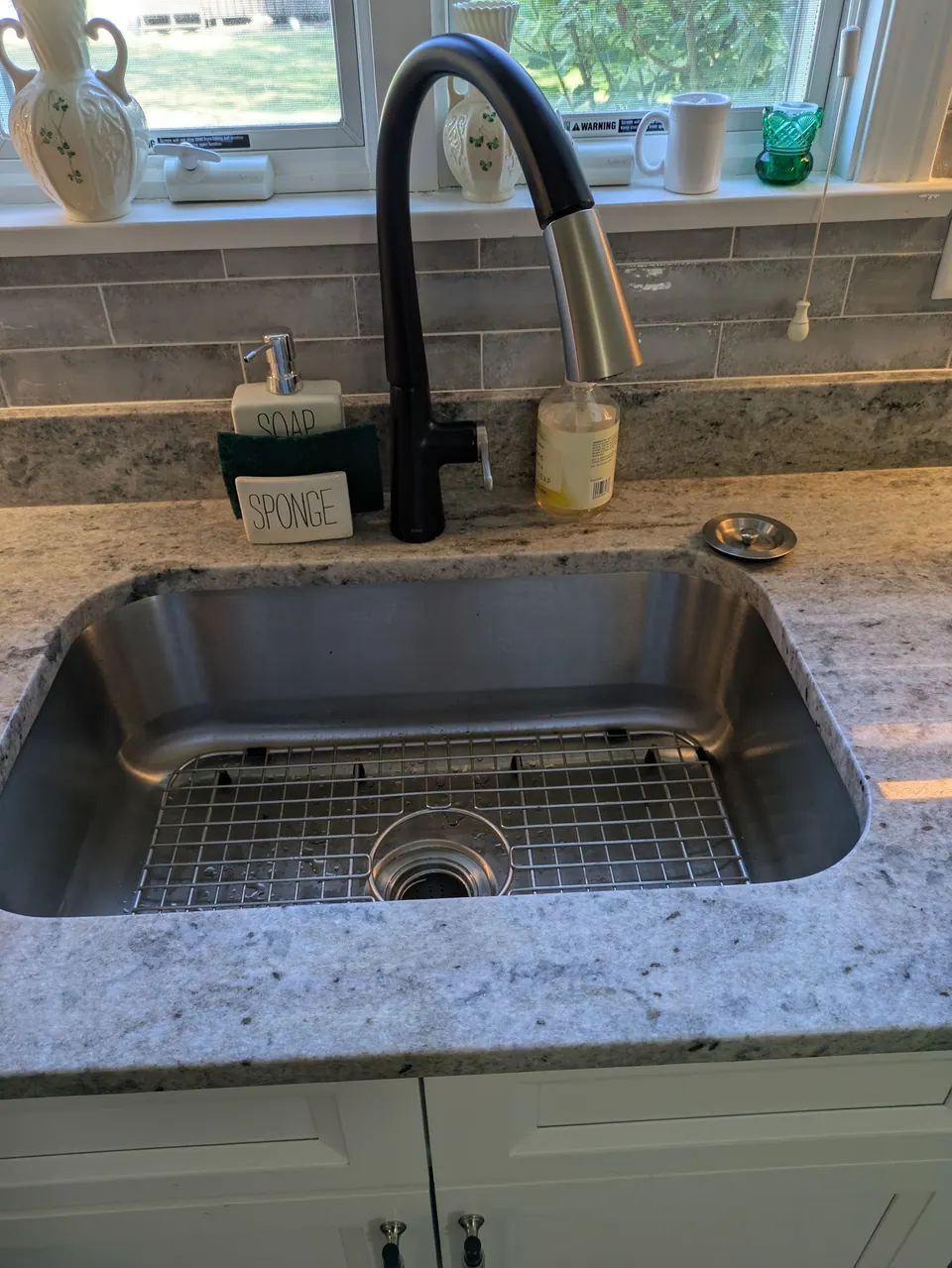 Undermount stainless sink with a black faucet set in a light gray countertop.