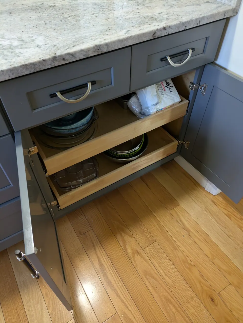 Gray base cabinet with both doors open, showing two wood roll-out trays.