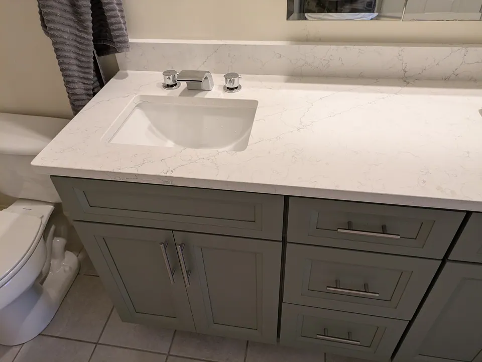 Bathroom: left end of the vanity with rectangular sink, chrome faucet and drawer stack.