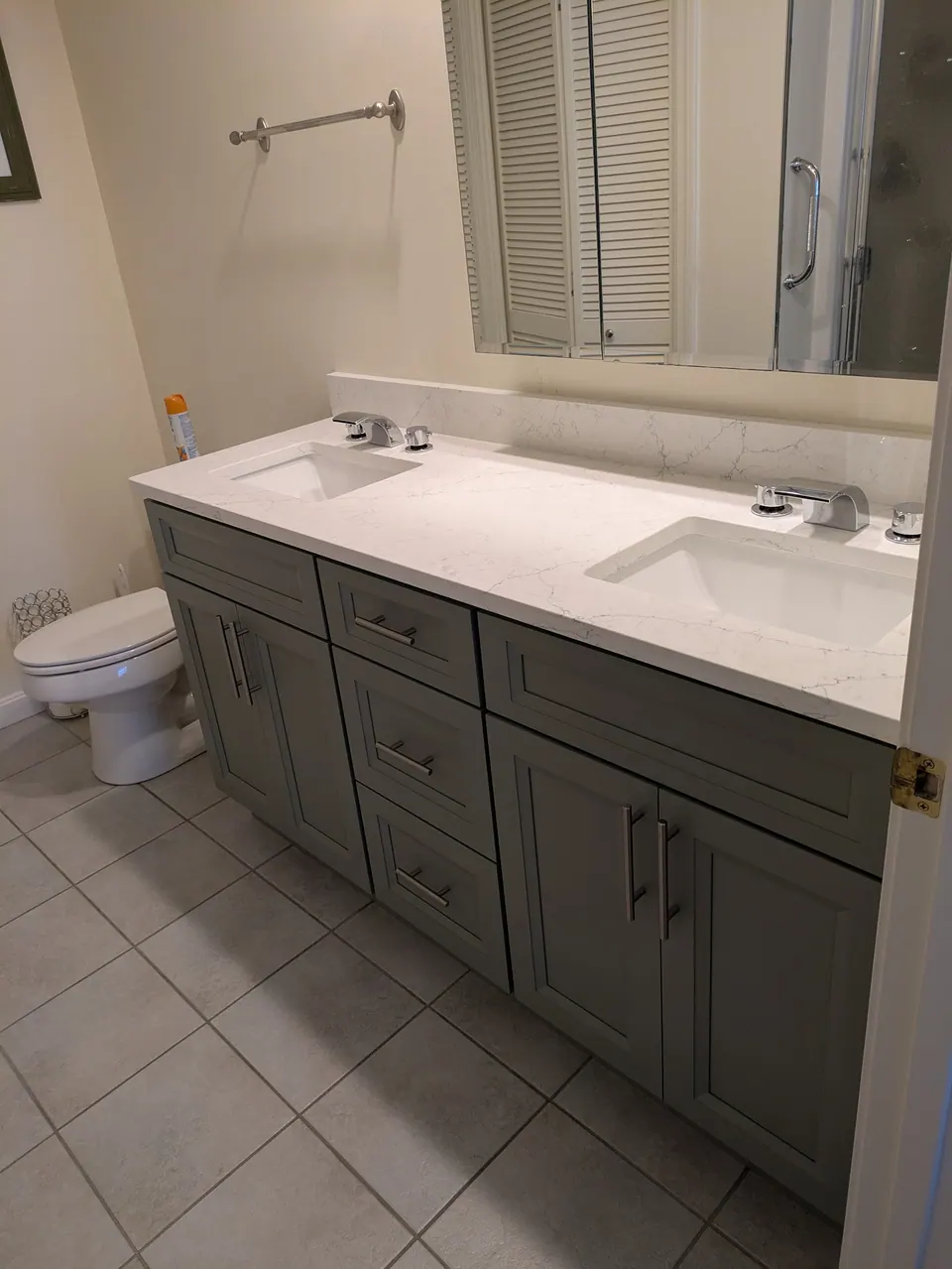 Bathroom: sage green double vanity with white veined countertop, two sinks and tile floor.