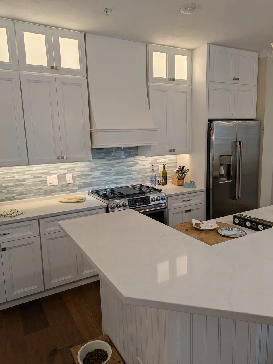 White perimeter cabinets and the island corner, with the range and refrigerator wall behind.