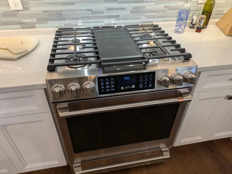 Gas range set between white drawer cabinets with a quartz counter.