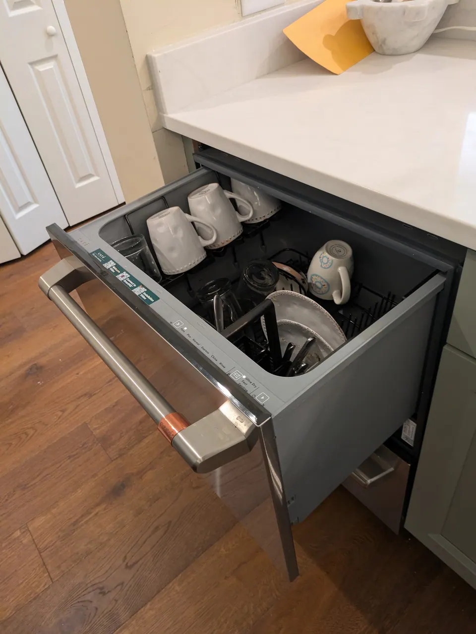 The lower dishwasher drawer open under the white quartz island top.