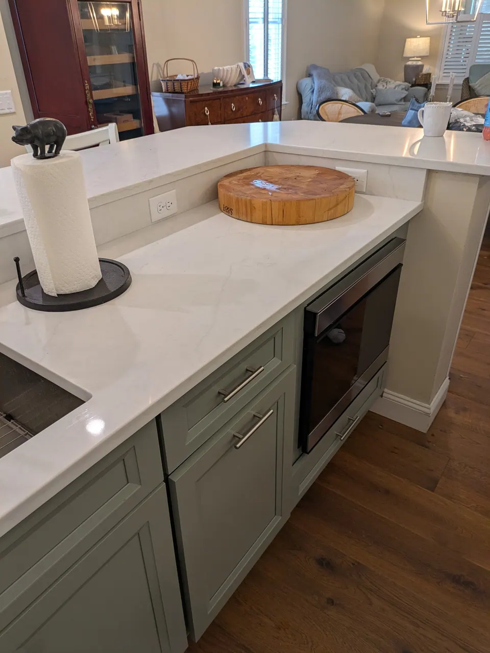 Sage green island cabinets with a microwave drawer under the counter.