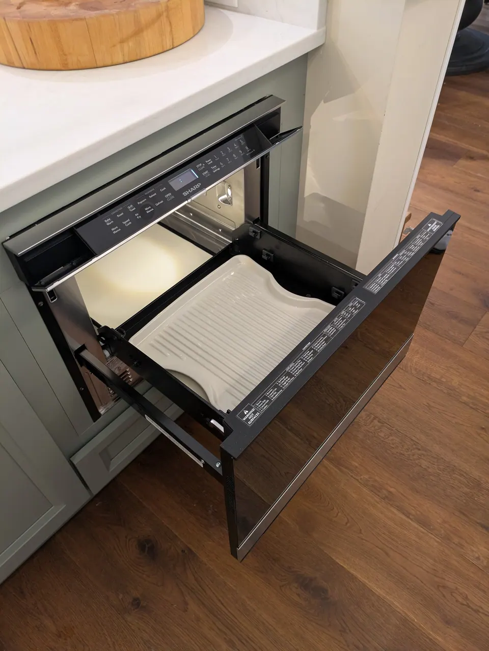 Microwave drawer open in the sage green island.