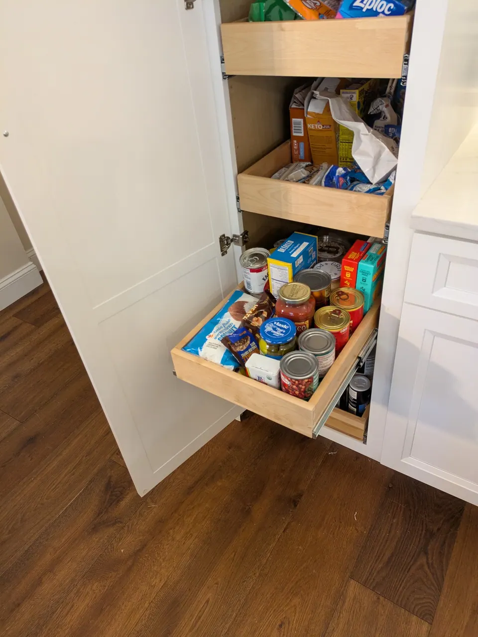 Pantry roll-out tray pulled out, full of groceries.