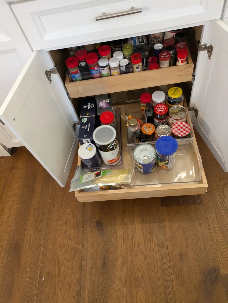 Base cabinet open with two pull-out shelves for spices and cans.