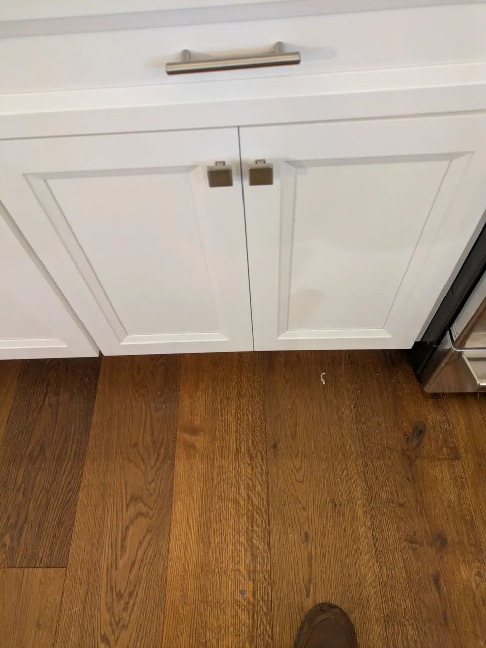 White base cabinet with a drawer over two doors and a wood floor.