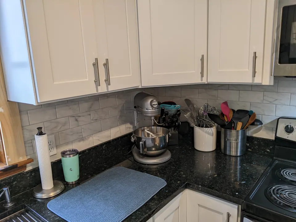 White wall cabinets over a black granite counter.