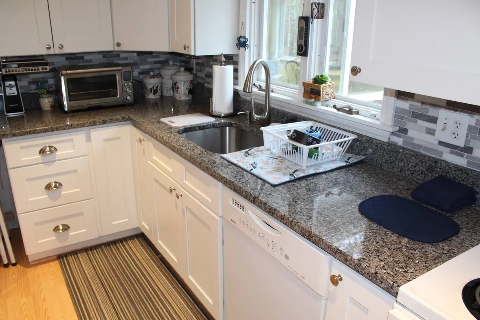 White shaker kitchen with a gray granite counter and a peninsula.