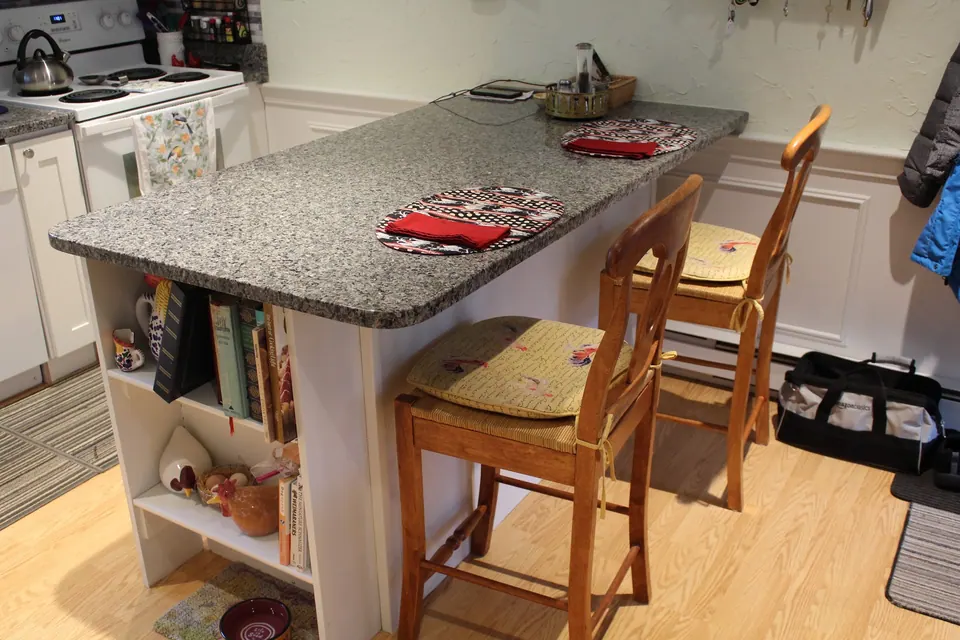 Peninsula with a gray granite top and stools.